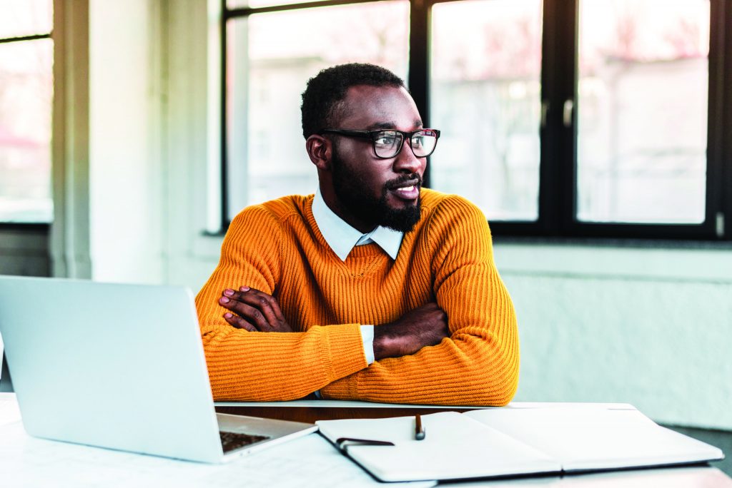 smiling african american businessman with crossed arms in office Man at desk